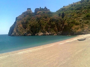 Perched atop a rocky cliff, this serene coastal retreat offers breathtaking views of the ocean and sandy beach below.