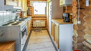 A compact kitchen with wooden cabinets, a stove, a microwave, and a coffee maker.
