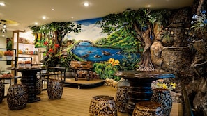 A room with a mural of a river and bridge, wooden furniture, and decorative vases.