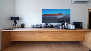 A modern kitchen with a wooden countertop, a toaster, coffee maker, and a painting of a volcanic landscape.