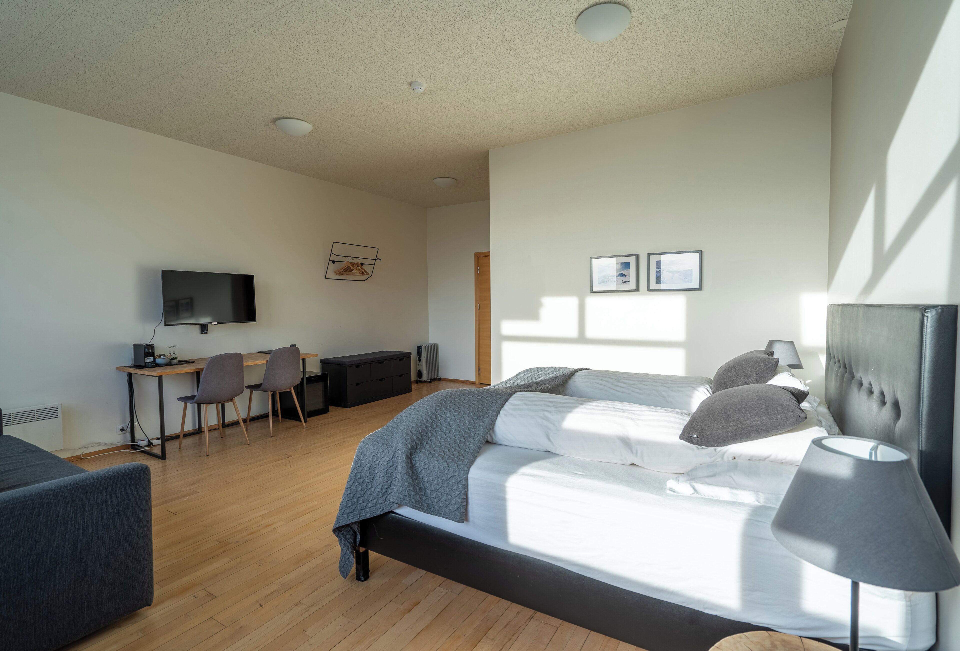 Un dormitorio moderno con cama, mesita de noche, lámpara y un escritorio con silla.