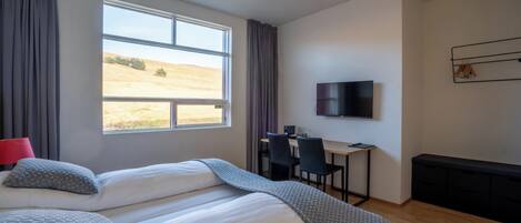 A bedroom with a large bed, a desk, and a TV.