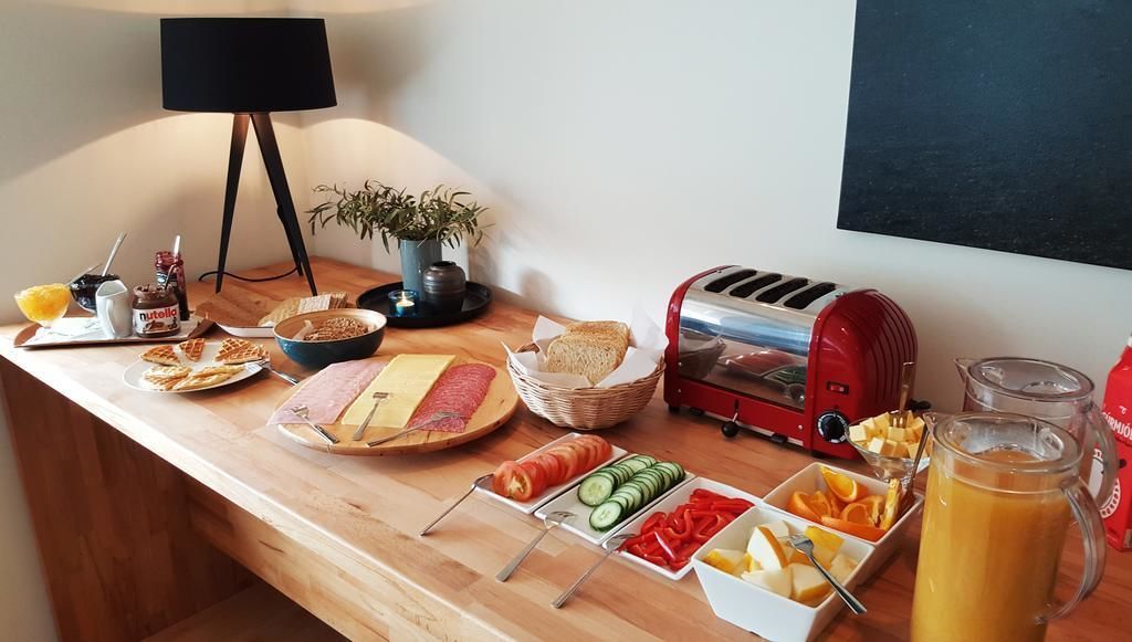 Un bufé de desayuno con diferentes alimentos, un tostador y una jarra de jugo de naranja.