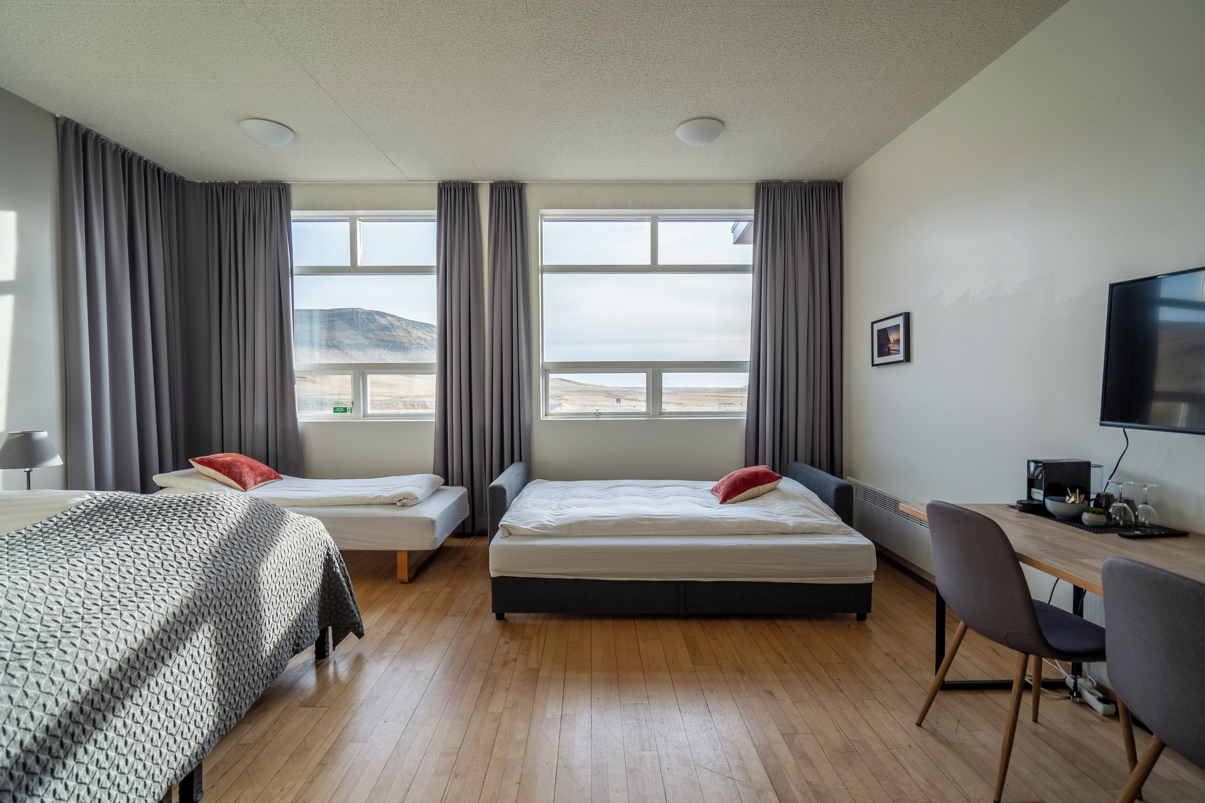 Una habitación de hotel con dos camas, un escritorio, una silla y un televisor.
