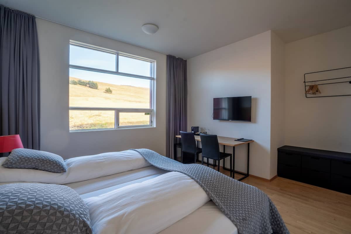 A bedroom with a large bed, a desk, and a TV.
