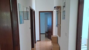 Corredor com portas de madeira, piso ladrilhado e um pequeno banco de madeira.