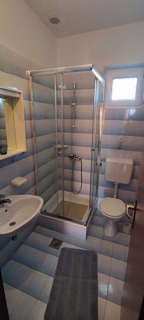 Et badeværelse med bruseniche, vask og toilet.