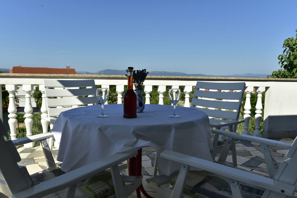 A table set for two with a bottle and glasses, overlooking a scenic view.