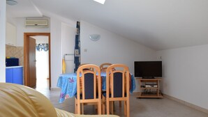 Un espace de vie compact comprenant un coin repas, un téléviseur et une kitchenette.