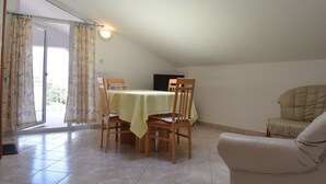 Un coin repas avec une table dressée pour quatre personnes, un canapé et une porte-fenêtre coulissante donnant sur un balcon.