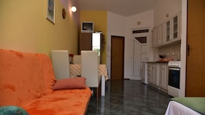 A compact living space with a sofa, a dining table, and a kitchenette.