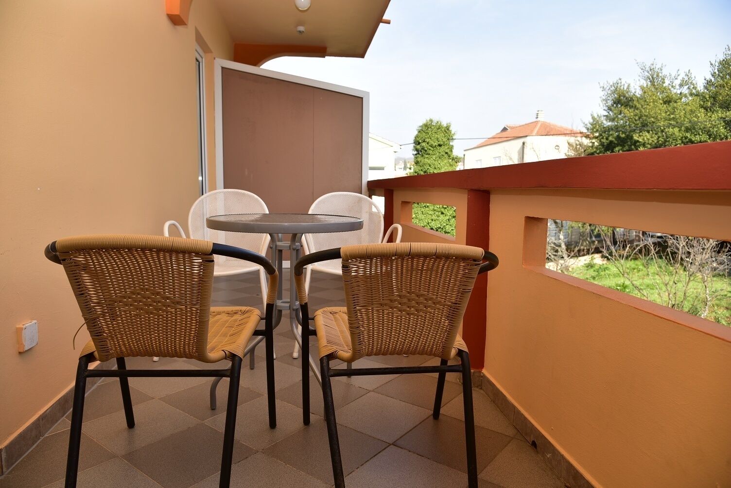 Ein Balkon mit zwei Korbstühlen und einem kleinen runden Tisch.