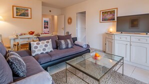 Ein modernes Wohnzimmer mit Sofa, Couchtisch und Fernseher. Es gibt eine Essecke mit Tisch und Stühlen.
