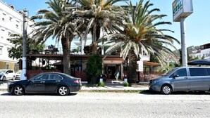Un hotel con un área de estar al aire libre techada, palmeras y un cartel que dice 'Vedar Hotel'.
