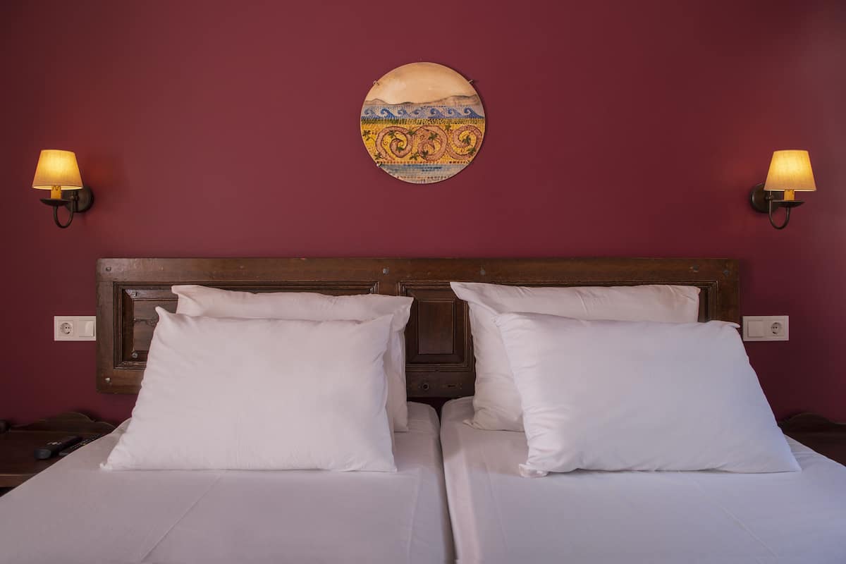 Ein Hotelzimmer mit zwei Betten, einem Holz-Kopfteil und zwei Wandleuchten.
