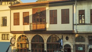 Un bâtiment arborant une enseigne indiquant qu’il s’agit d’un hôtel-boutique, doté de grandes fenêtres en arc de cercle et d’un balcon orné d’une balustrade en fer forgé.