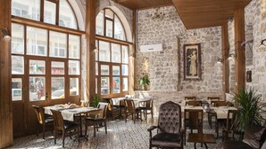 Un restaurant aux murs de pierre, aux meubles en bois et aux grandes fenêtres.