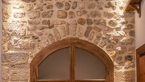 Une pièce avec un mur en pierre, une porte en bois dotée de panneaux de verre, un banc en bois et une table en bois.