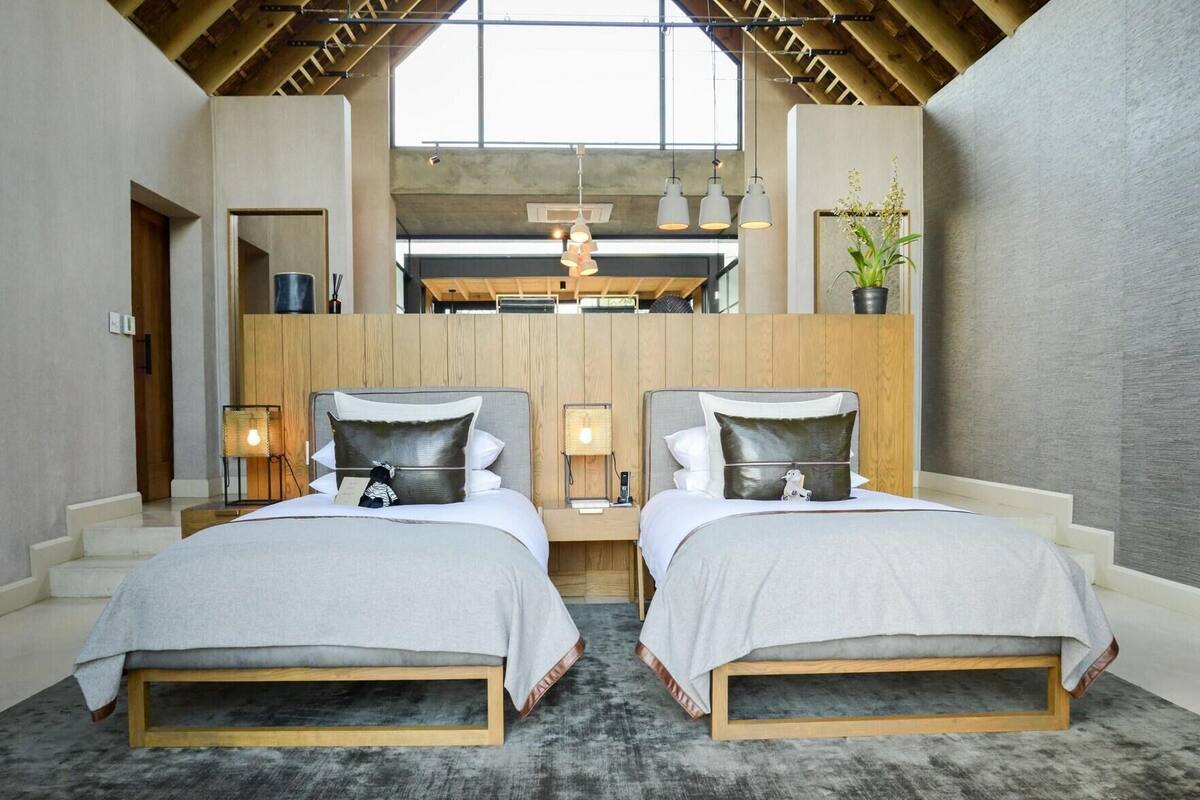 Ein modernes Schlafzimmer mit zwei Betten, einem Oberlicht und einer Holzbalkendecke.