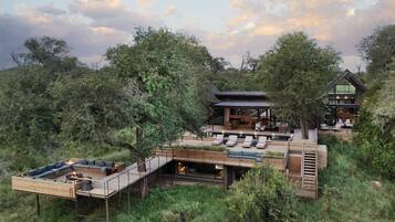 A modern, multi-level outdoor living space with a dining area, lounge chairs, and a fire pit.