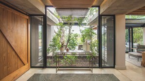 A modern interior with a glass door leading to a garden, a wooden wall, and a metal-framed table with potted plants.
