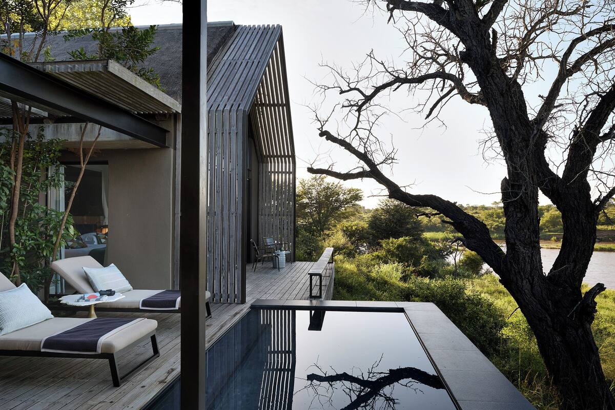 Eine moderne Lounge-Bereich im Freien mit Pool, Holzterrasse und Blick auf eine natürliche Landschaft.
