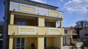 A two-story building with balconies, a patio area, and potted plants. - Apartments Mermaid (Malinska-Dubasnica)