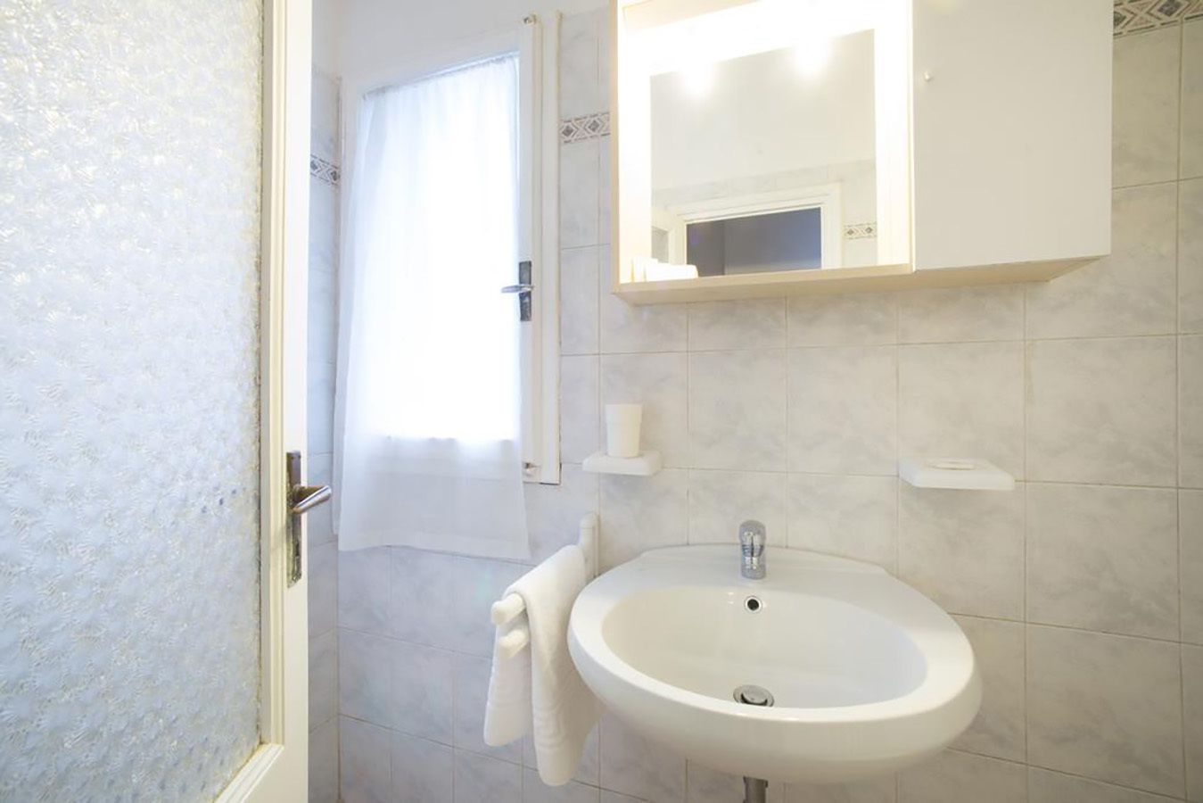 A bathroom with a white sink, a mirror above it, and a towel hanging on the wall.