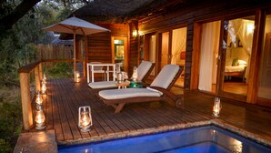 A wooden deck with a pool, lounge chairs, and candles. - Lion Sands Narina Lodge (Mbombela)