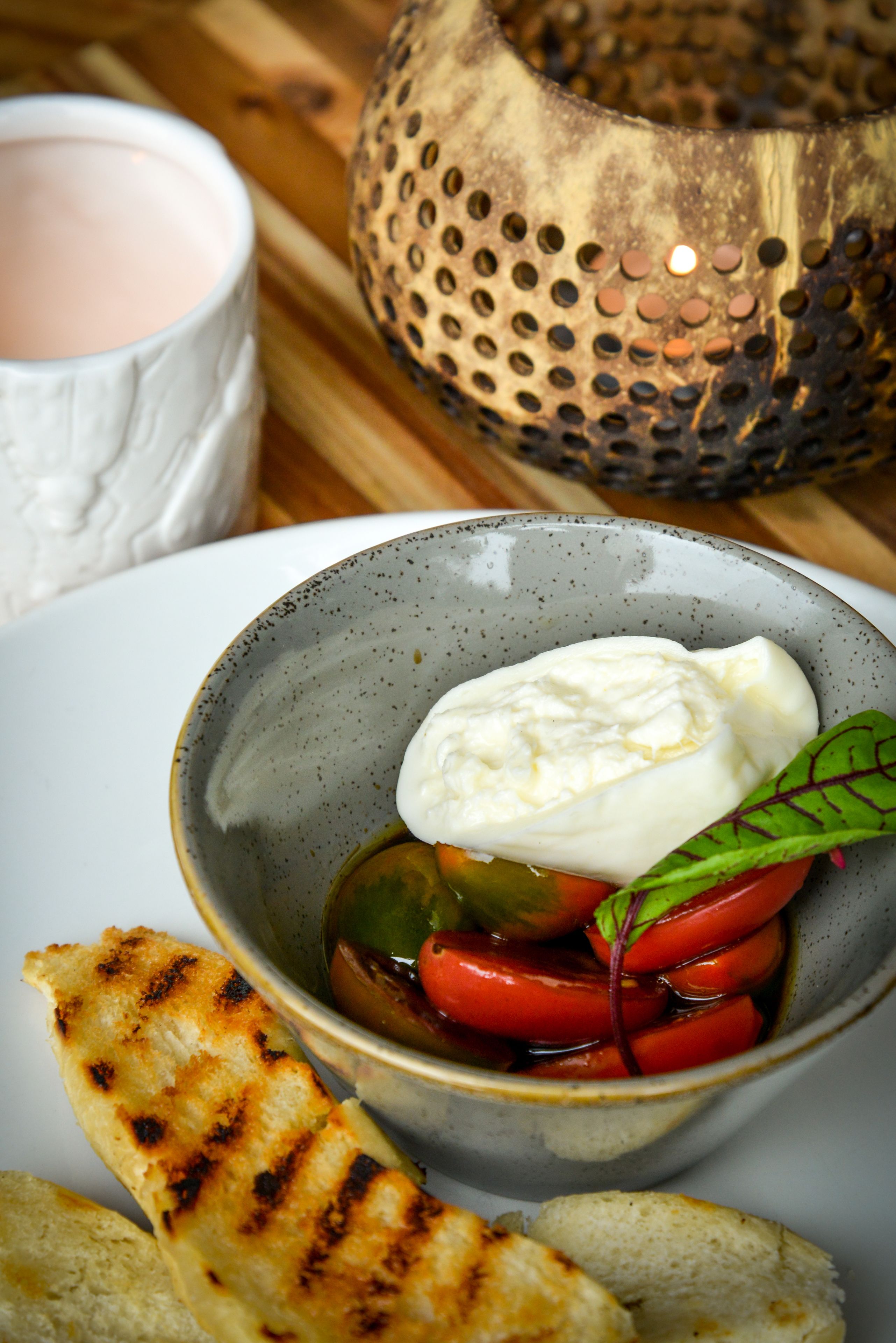 A bowl of Caprese salad with grilled bread on a white plate.