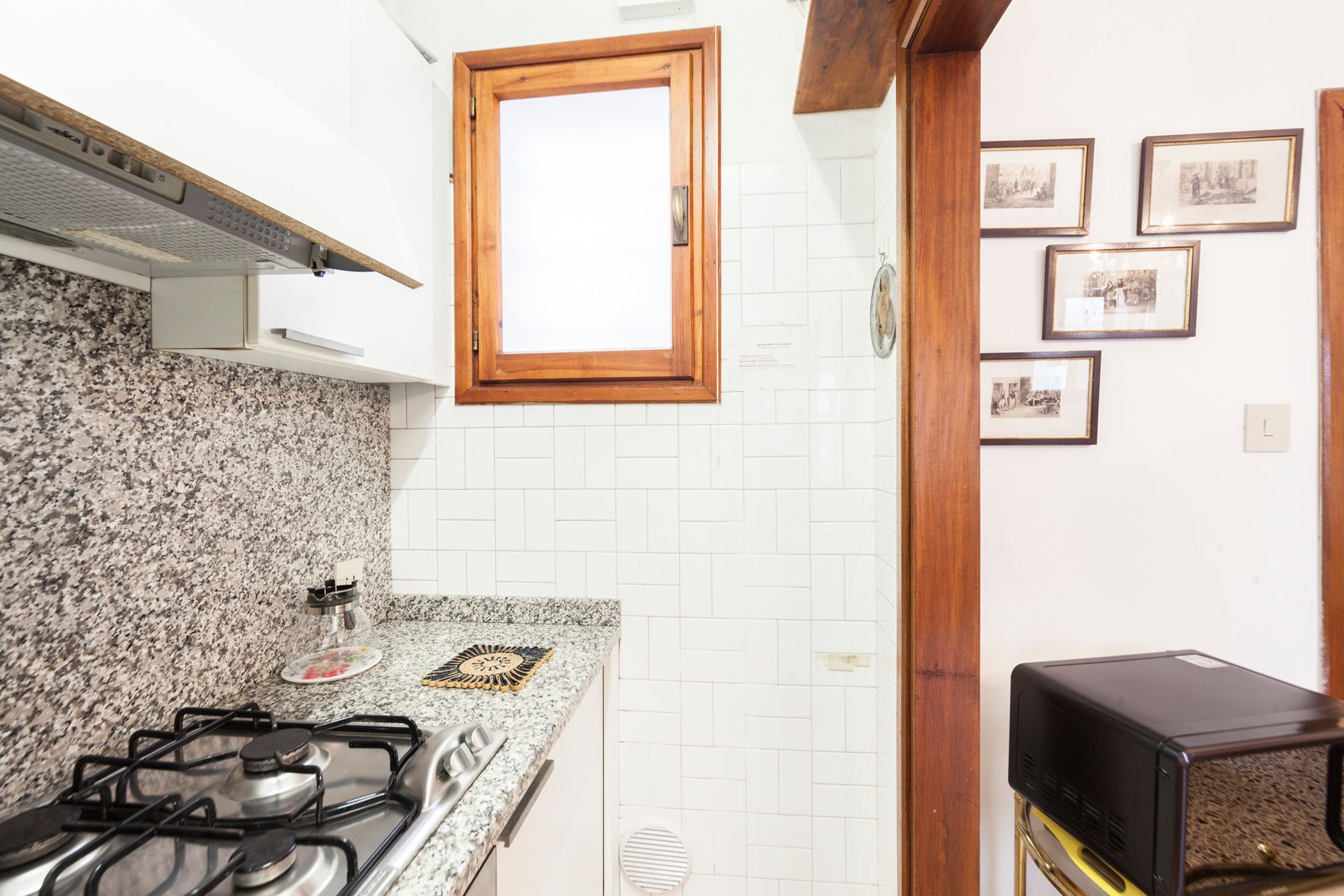 Une cuisine dotée de plans de travail en granit, d’une cuisinière à gaz, d’un four à micro-ondes et d’une fenêtre à cadre en bois.