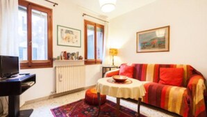Ein gemütliches Wohnzimmer mit einer Couch, einem kleinen Tisch, einem Heizkörper und einem Bücherregal.