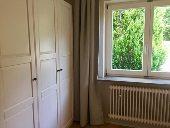 A room with a window, a radiator, and a set of white doors.