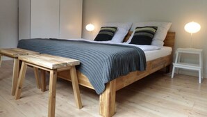 A bedroom with a wooden bed, a bedside table, a nightstand, and a wardrobe.