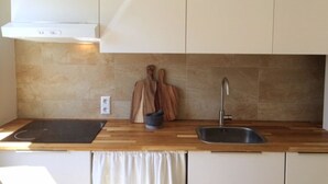 A modern kitchen with a wooden countertop, a sink, and a stove.