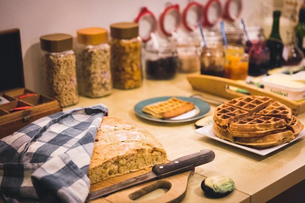 A kitchen counter with a loaf of bread, a waffle, and various jars of spices.