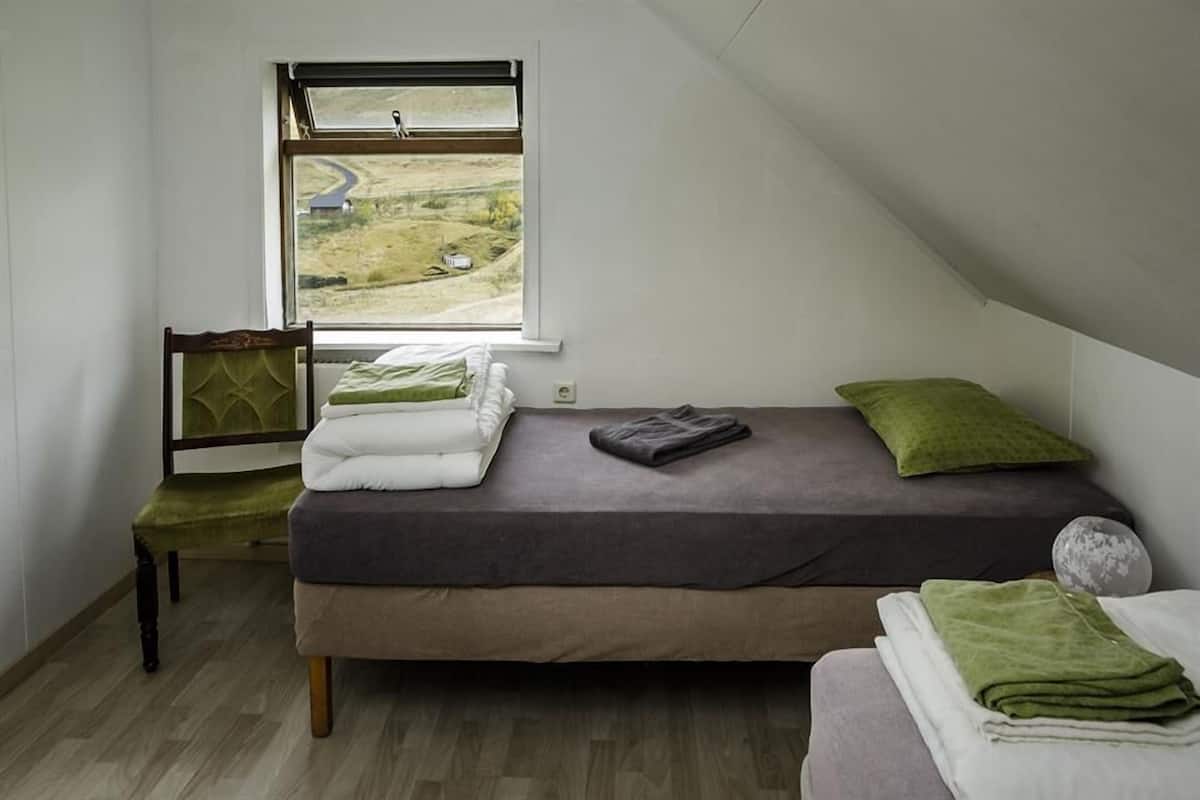 Een kleine kamer met een enkel bed en uitzicht op een landelijk landschap door het raam.