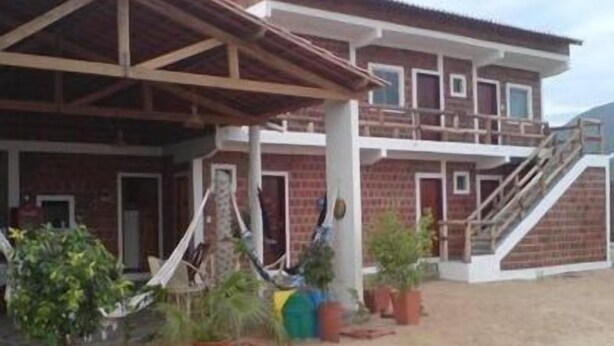 A two-story building with a covered patio area, multiple windows, and a staircase leading to the upper level. - Pousada Brisa Da Serra em Sobral (Sobral)