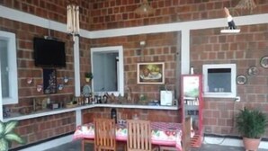 A brick-walled room with a dining table, chairs, a TV, and a small window. - Pousada Brisa Da Serra em Sobral (Sobral)