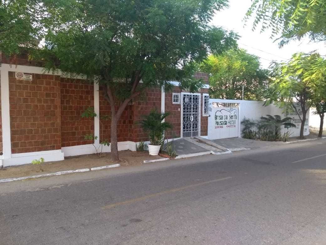 A brick building with a gated entrance, a signboard, and a tree in front.