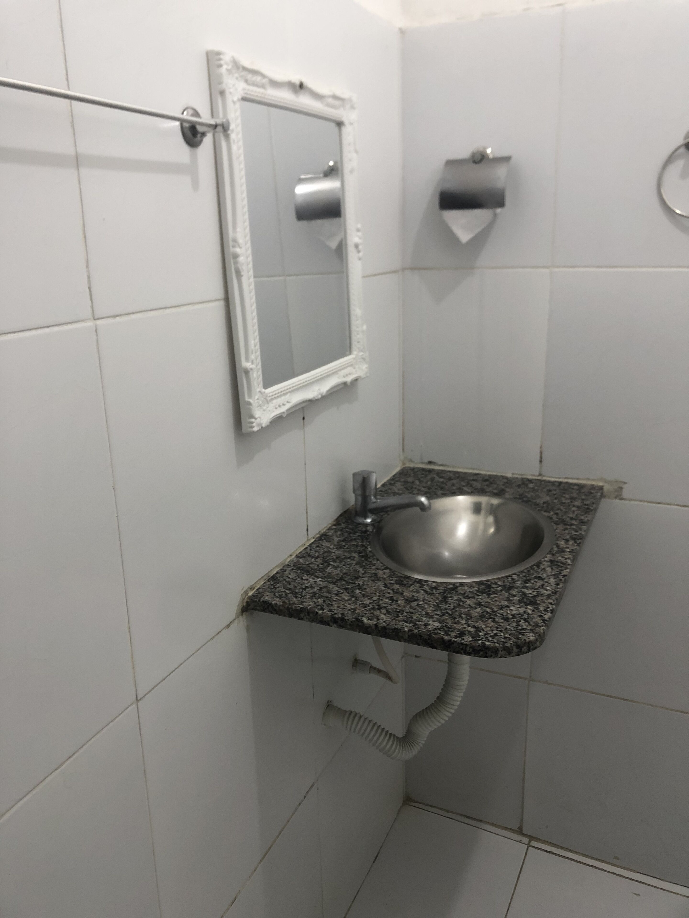 Baño con lavamanos de encimera de granito, espejo y dispensador de toallas.
