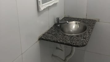 Baño con lavamanos de encimera de granito, espejo y dispensador de toallas.