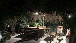 An outdoor seating area with wooden benches and tables, surrounded by lush greenery and a thatched roof structure. - Pousada Brisa Da Serra em Sobral (Sobral)