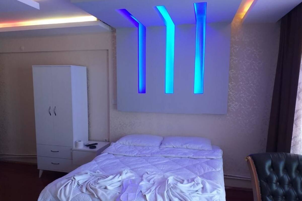 A hotel room with a bed, a wardrobe, and a chair.