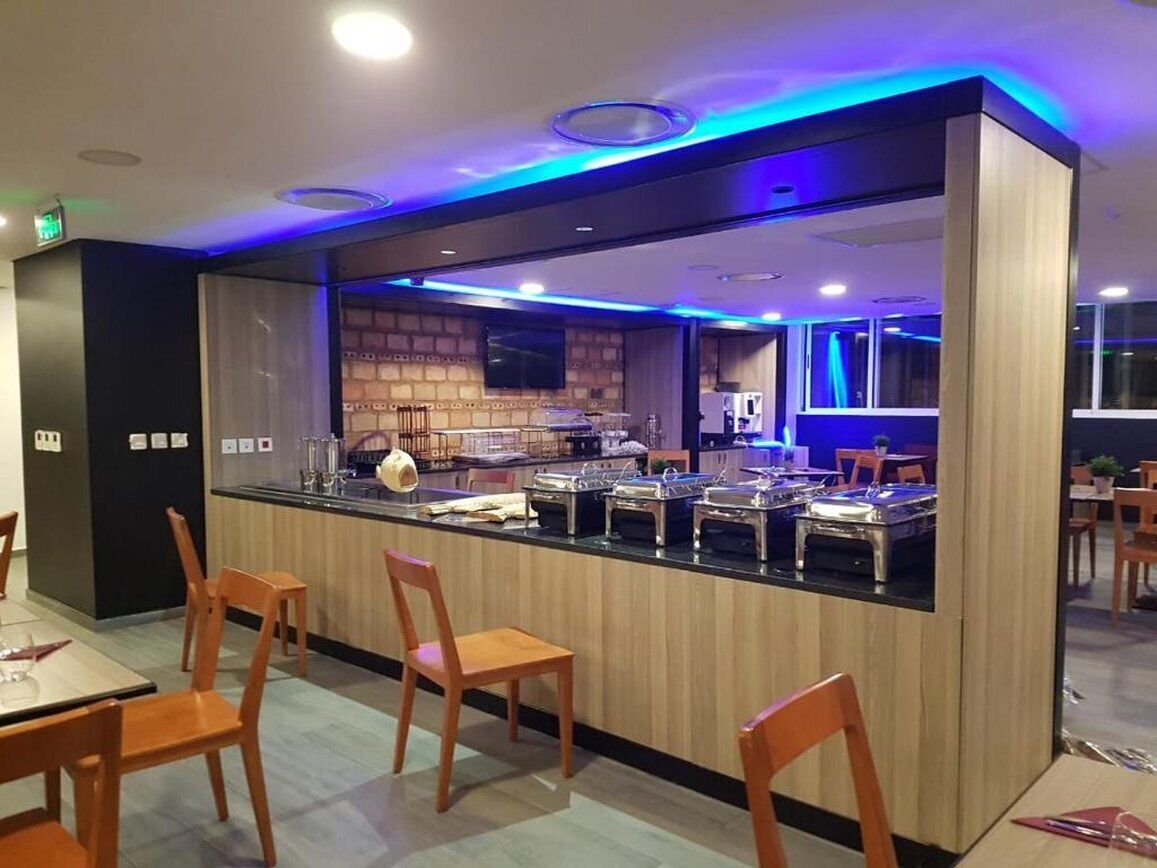 Zona de buffet amb taulell, cadires i cuina al fons.