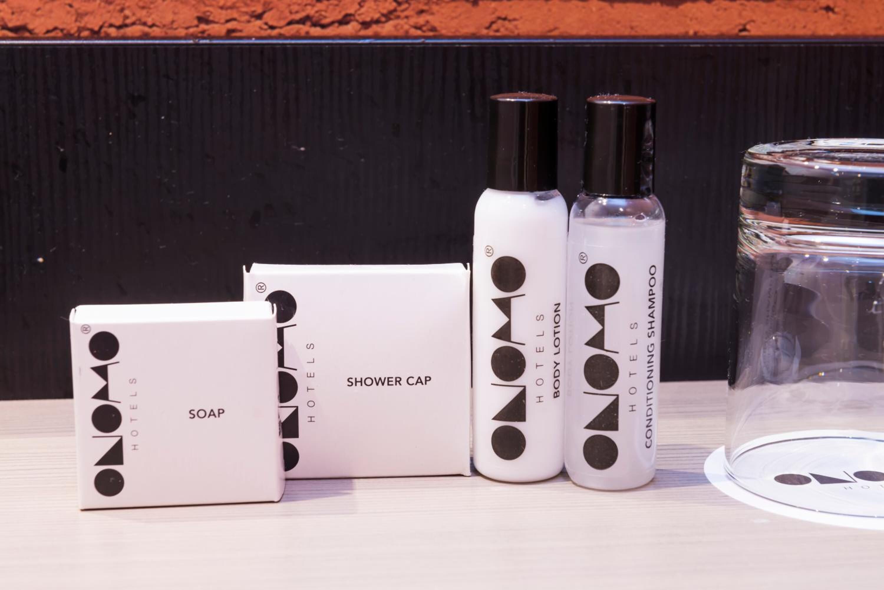 Un ensemble de produits de toilette d’hôtel comprenant un bonnet de douche, du savon et une lotion pour le corps.
