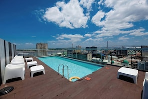A rooftop pool area with a clear view of a bridge and buildings in the background.