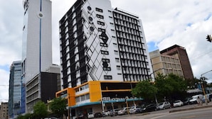 A modern hotel with a distinctive black and white geometric facade, multiple floors, and a visible clock on the side. - ONOMO Hotel Maputo (Maputo)