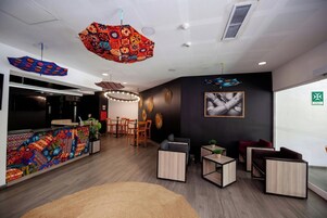 Un interior moderno con una recepción, zona de estar y detalles decorativos en el techo.