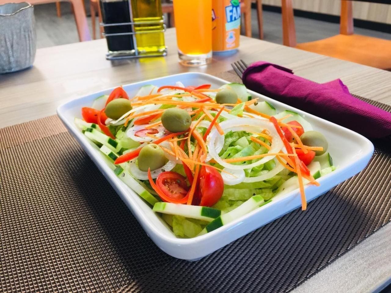 A rectangular white plate with a salad on a table.